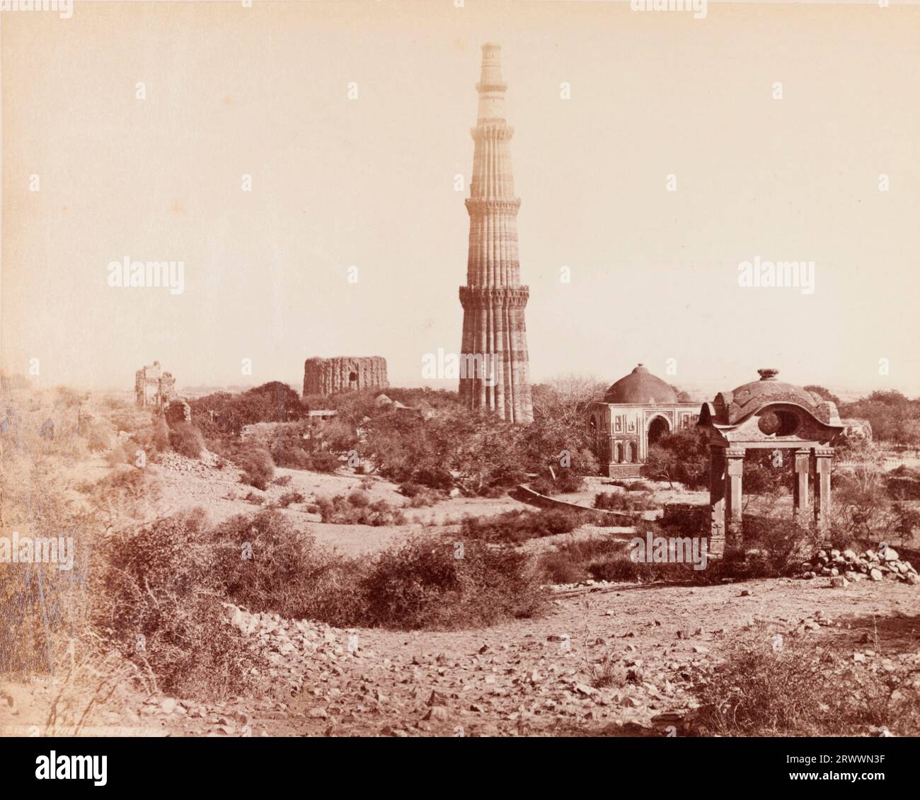 View of the Qutub Minar. At 72.5 metres tall, this was built as a celebratory victory tower to accompany the Quwwat-ul-Islam mosque. The scene shows the victory minaret surrounded by ruins. Inscribed on negative: Frith's Series. 3124 Kutub Minar: Delhi. Caption reads: Kutub Minar & Ruins, Delhi. Stock Photo