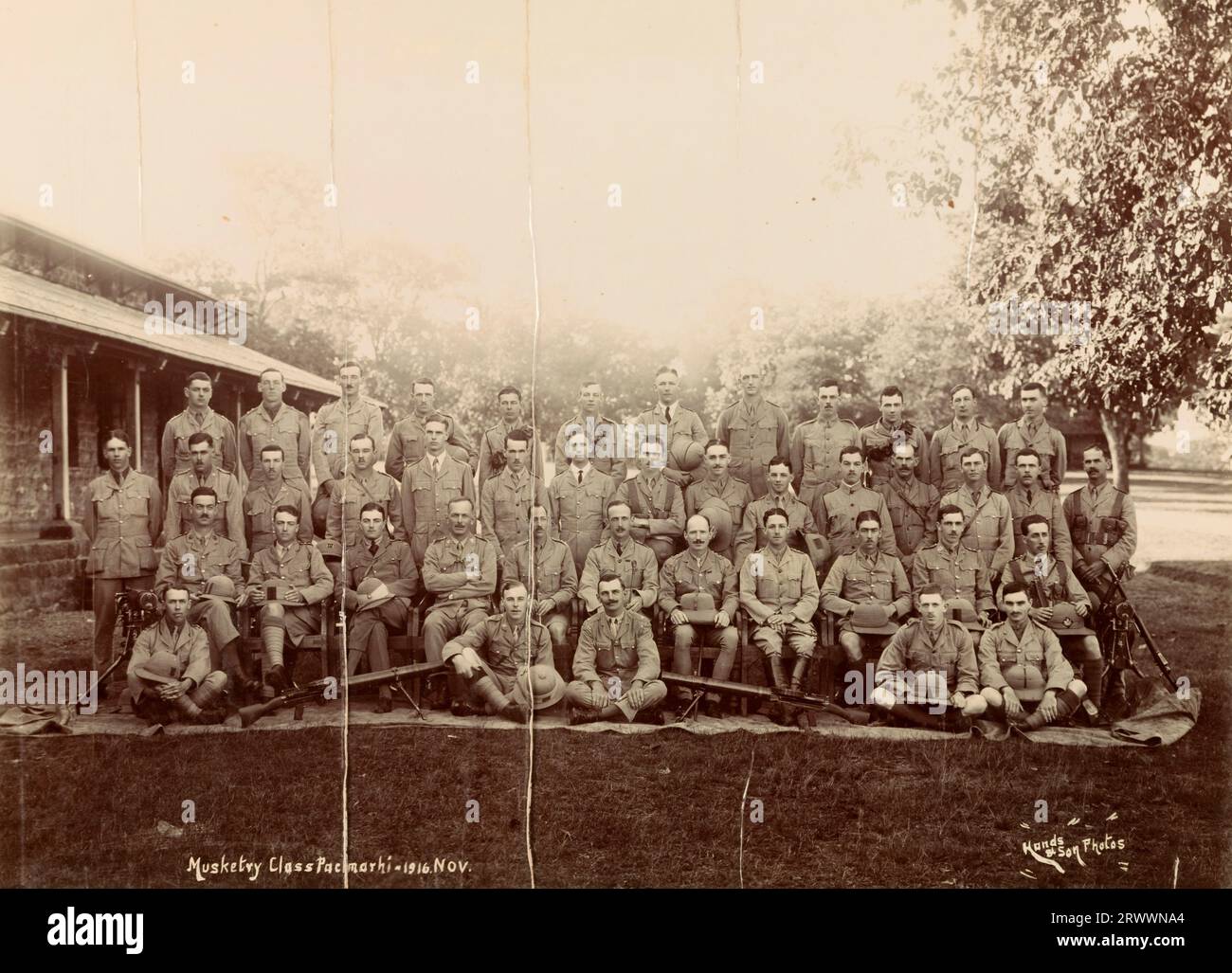 Trainee British musketeers pose for a group portrait with their rifles outside the School of Musketry at Pachmarhi. Winthrop studied for this course at Pachmarhi from October -December 1916.  Printed caption: Musketry Class Pachmarhi - 1916. Nov. Hands & Son Photos. Stock Photo