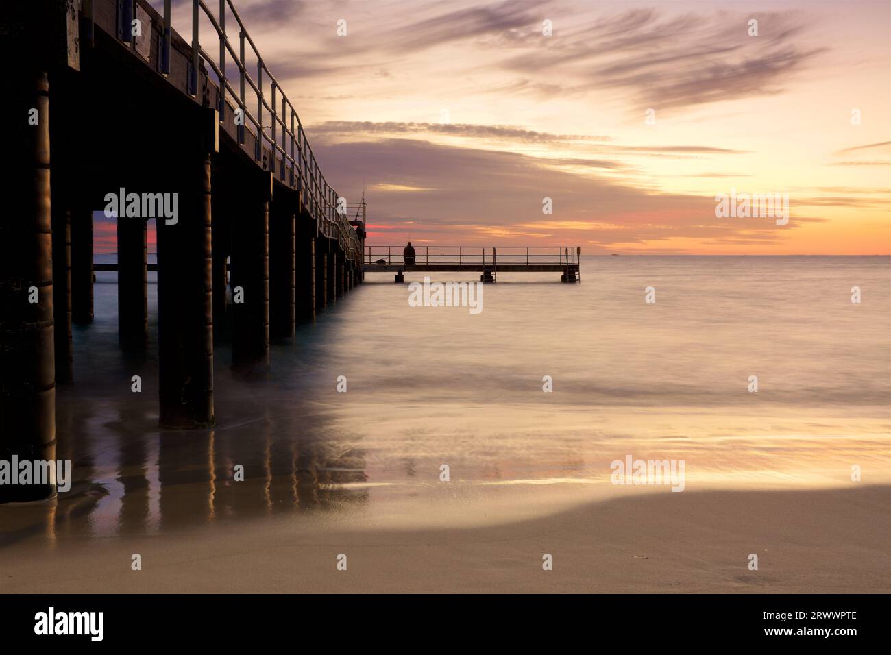 Sunset at Coogee Beach Jetty with a person fishing in the southern suburbs of Perth, Western Australia Stock Photo
