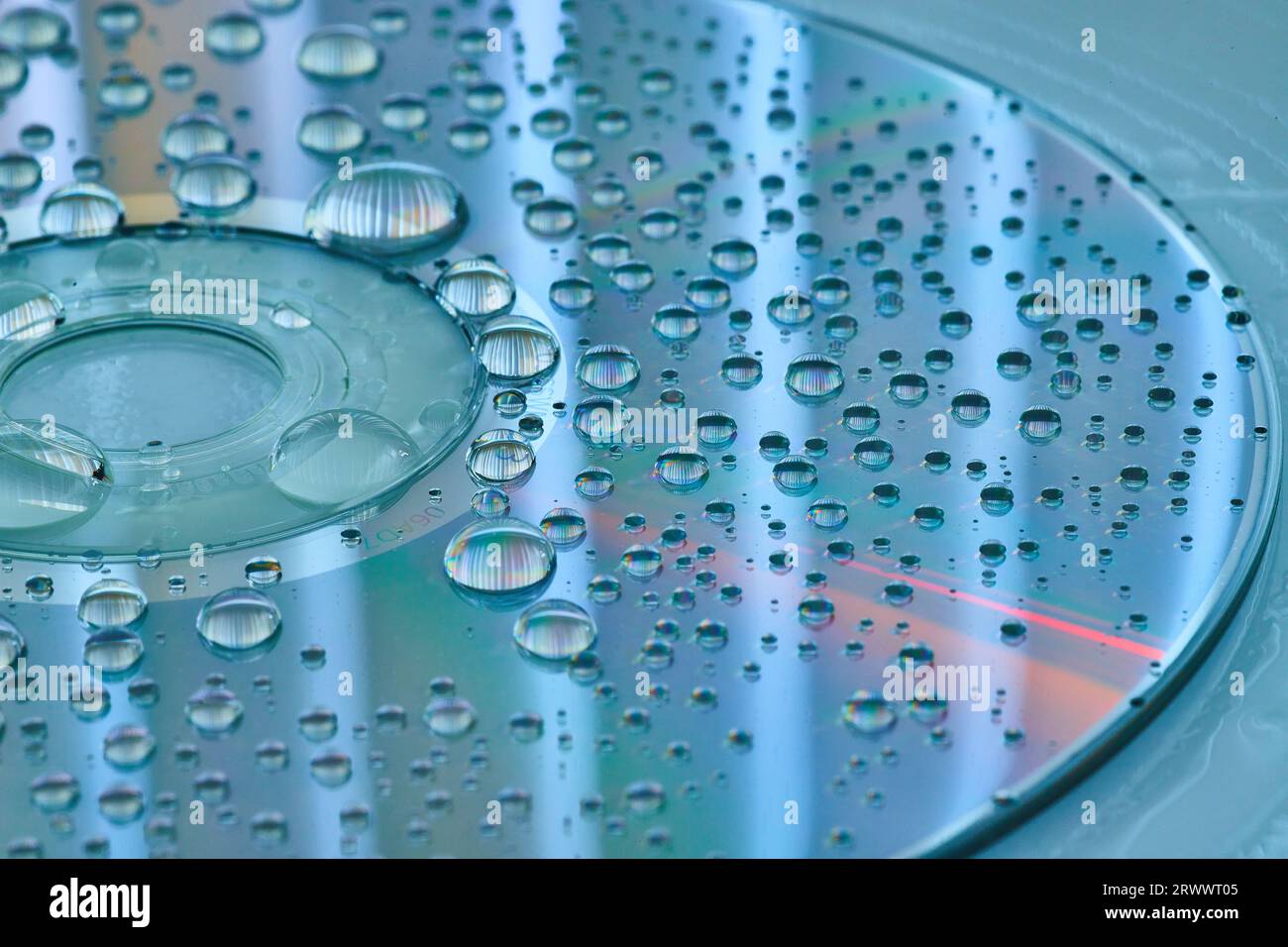 Calm blue and silver surface with silvery water droplets on CD surface and slate blue background Stock Photo