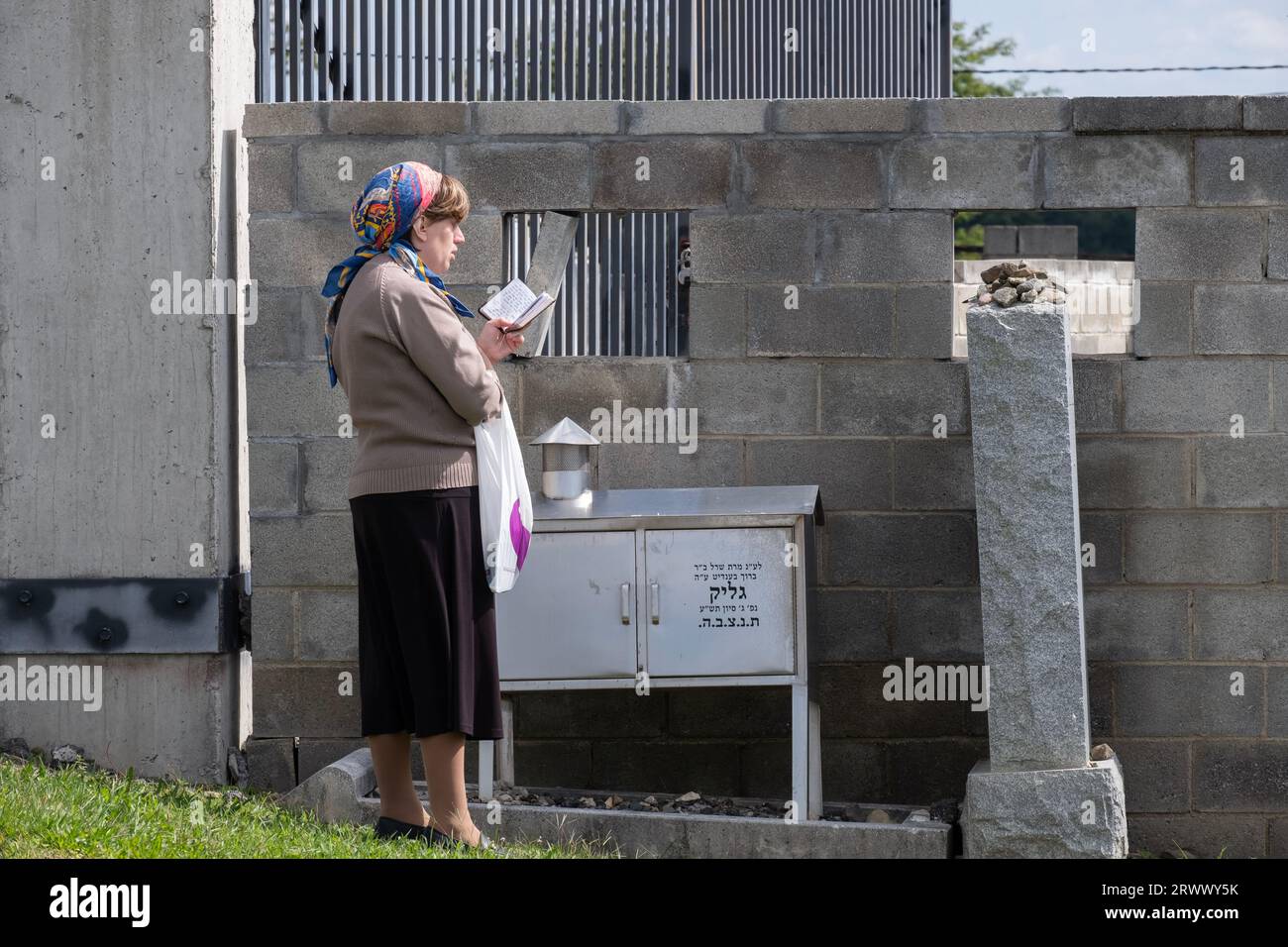 An orthodox Jewish woman prays at a headstone at a Jewish cemetery in Orange County, New York. Stock Photo
