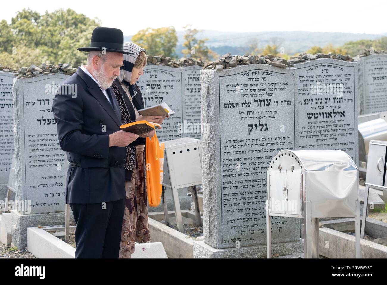 A hasidic couple pray at the headstone of a family member at the Old