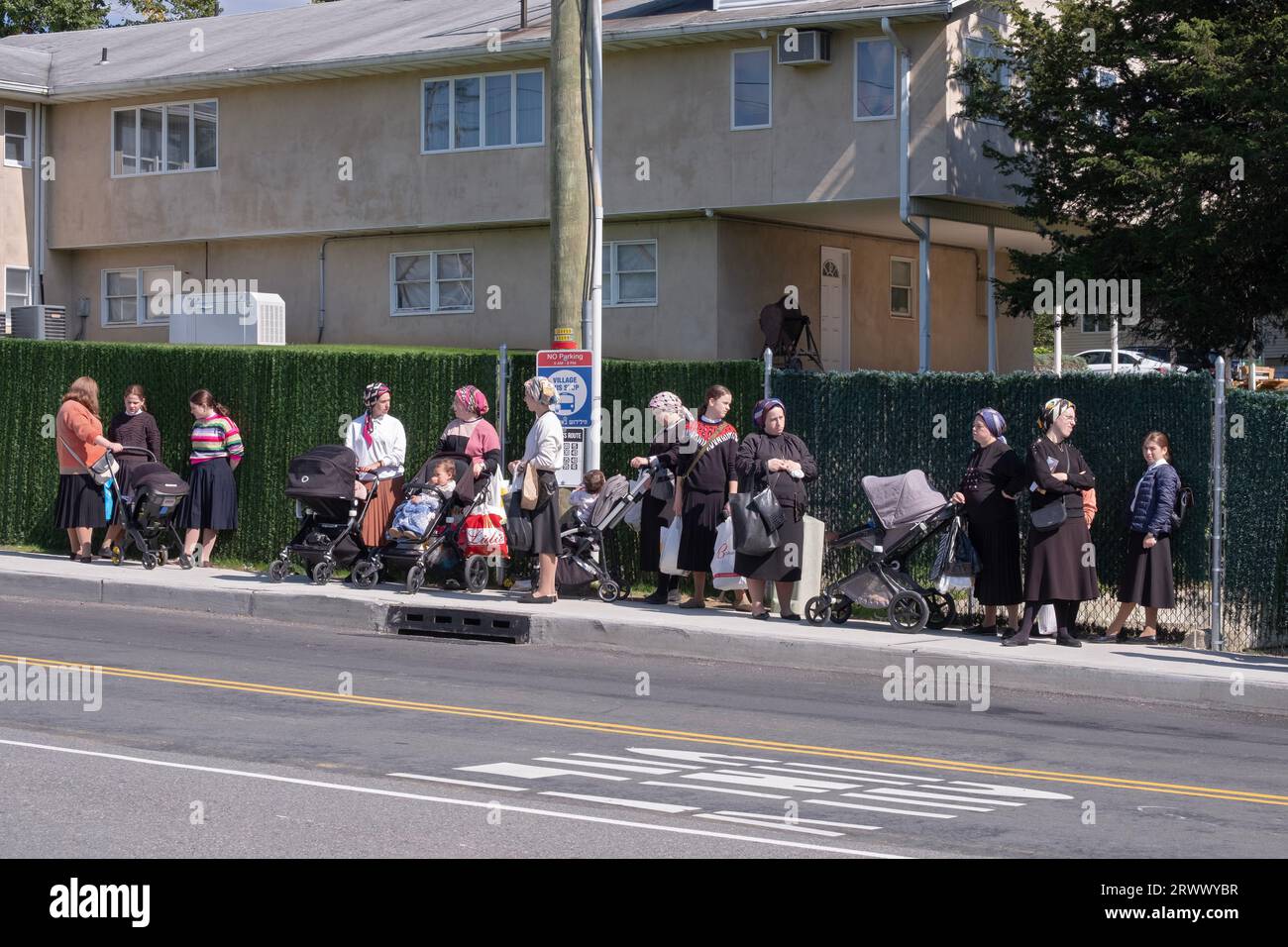 A group of modestly dressed orthodox Jewish women wait for a bus on