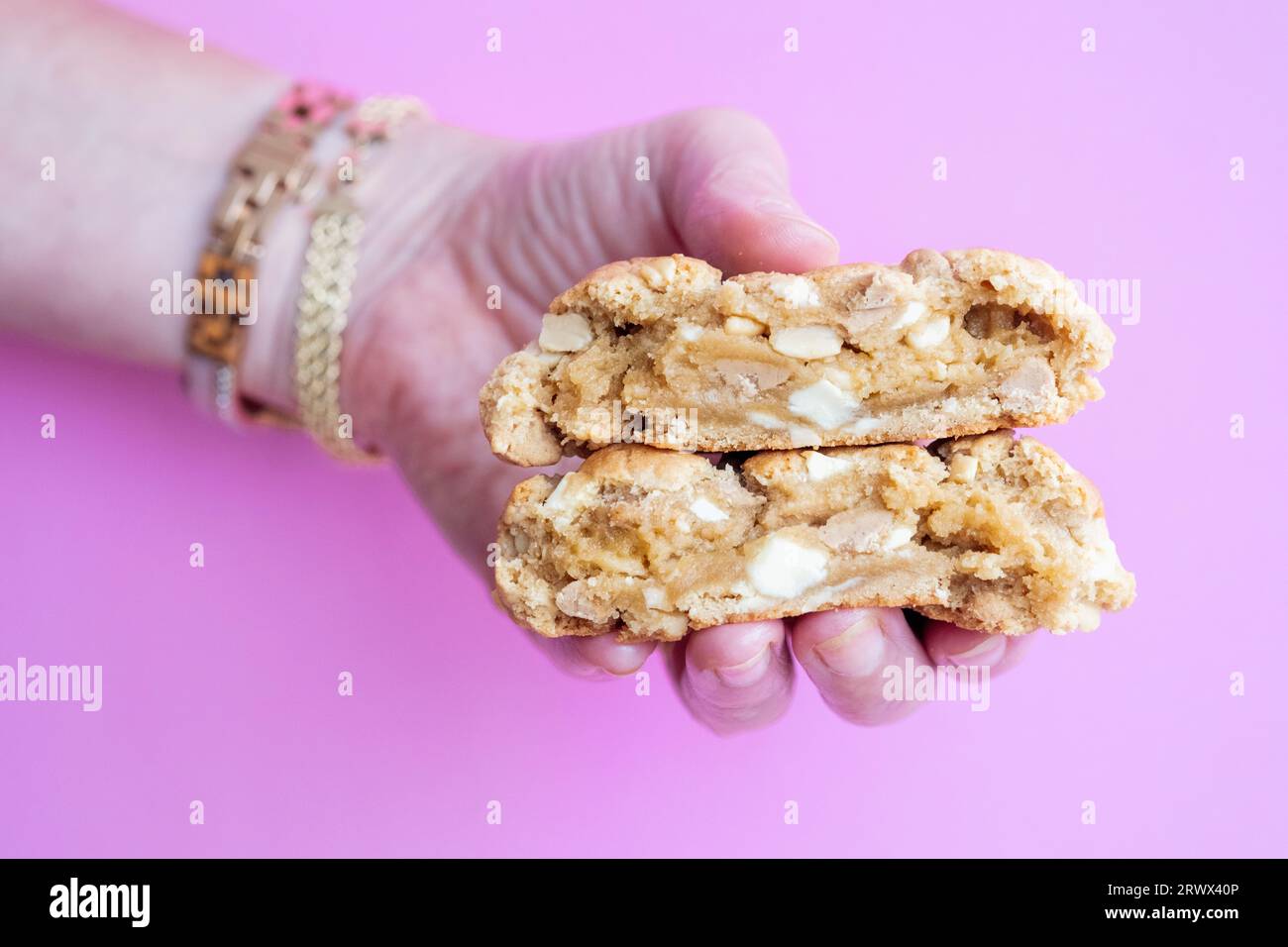A woman holding a broken in half homemade New York style peanut butter Chip Cookie. Its a  large cookie with a  crisp outer crust and soft centre. Stock Photo