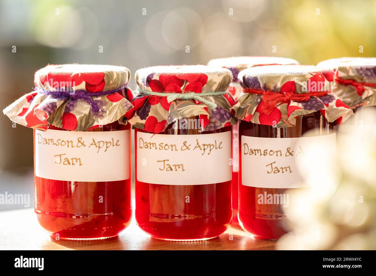 Jars of homemade Damson and Apple jam. The glass jars have clear handwritten labels and each jar has a cloth topping. Stock Photo