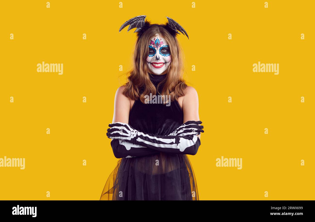 Smiling girl in creative skeleton costume and bat wings on her head