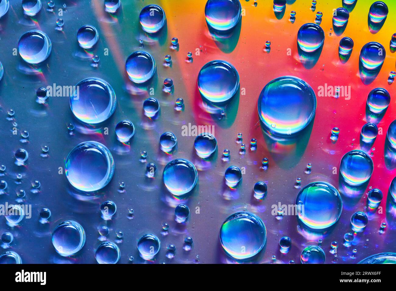 Silvery blue water droplets on colorful red and orange metallic surface background asset Stock Photo