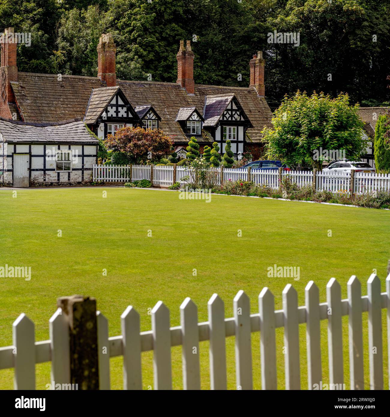 Bowling green with white picket fence and traditional country cottages behind in the English countryside Stock Photo