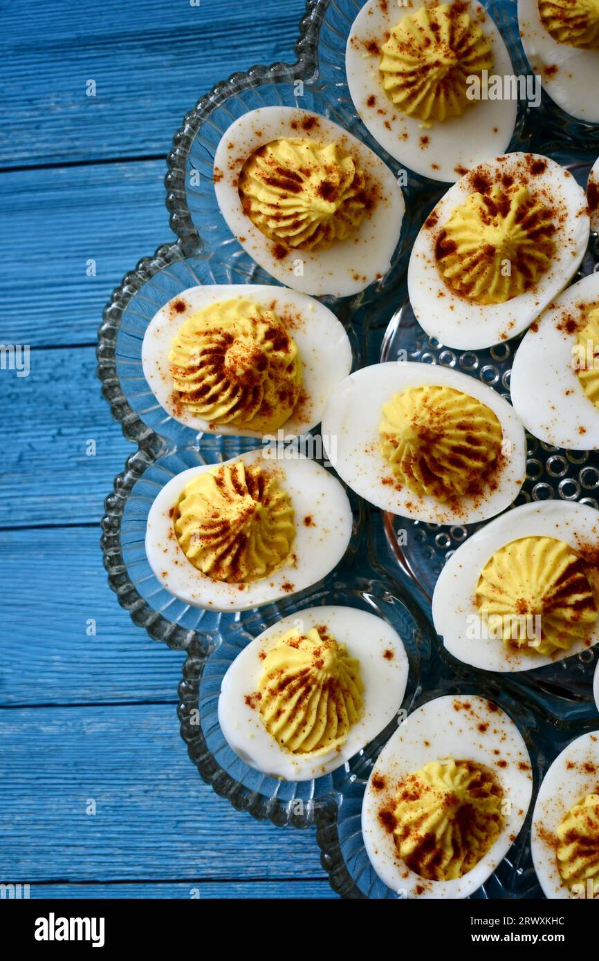 Deviled eggs in a decorative glass dish on a bright blue wooden background viewed from above Stock Photo