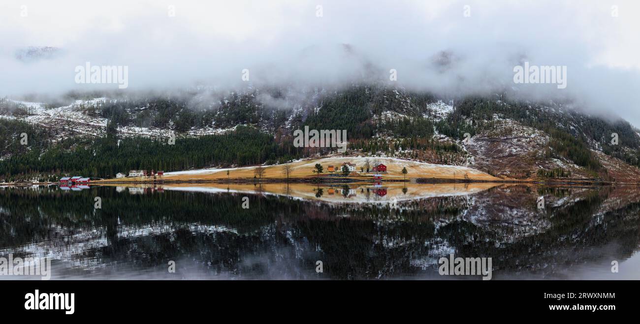 Autumn in norwegian mountains. Panorama of a blue transparent lake reflecting mountains covered with evergreen coniferous spruce forest, a mountain fa Stock Photo