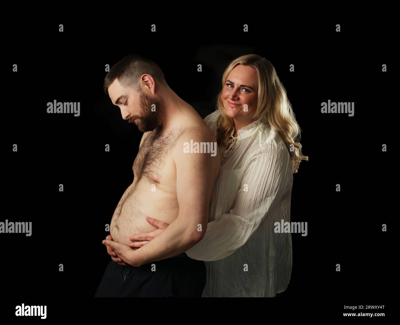 Couple pose but with the male pretending to be pregnant. Stock Photo