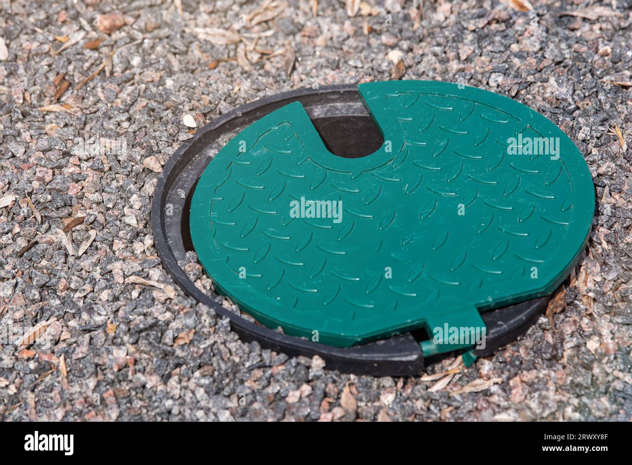 A plastic hatch in the garden covering the connection point for the irrigation hose. A protective hatch in the garden for connecting water and Stock Photo