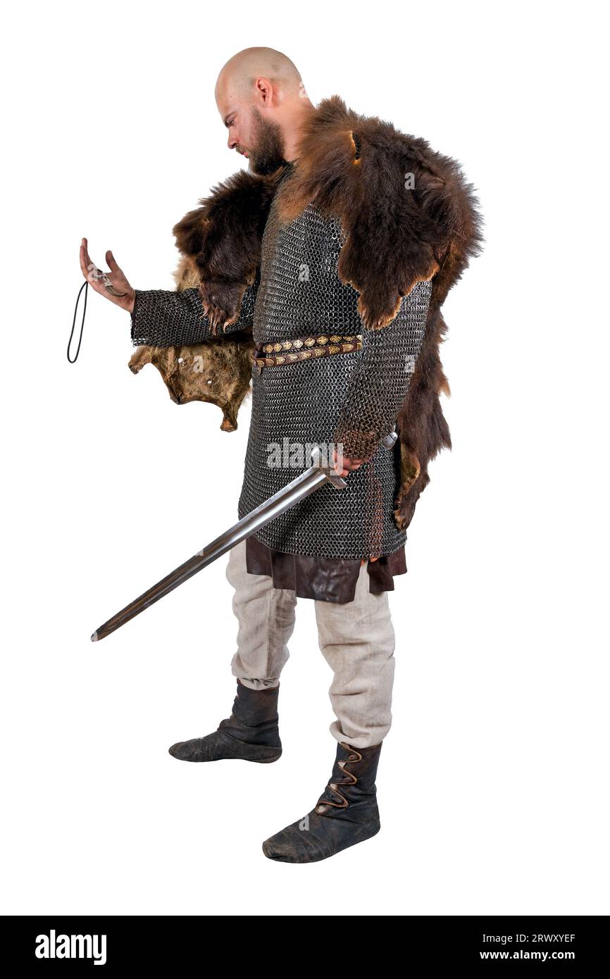 Medieval Viking with a sword in a bearskin, examines the decoration in the form of a bear tooth. Isolated on white Stock Photo