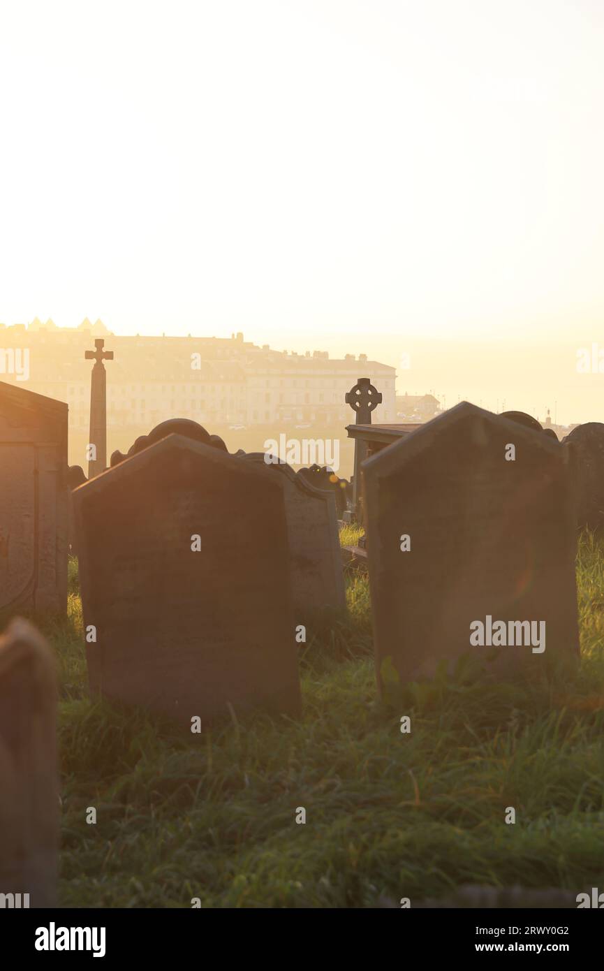Sunset over the graveyard of historic St Mary's Church on windswept East Cliff by Whitby Abbey in North Yorkshire, UK Stock Photo