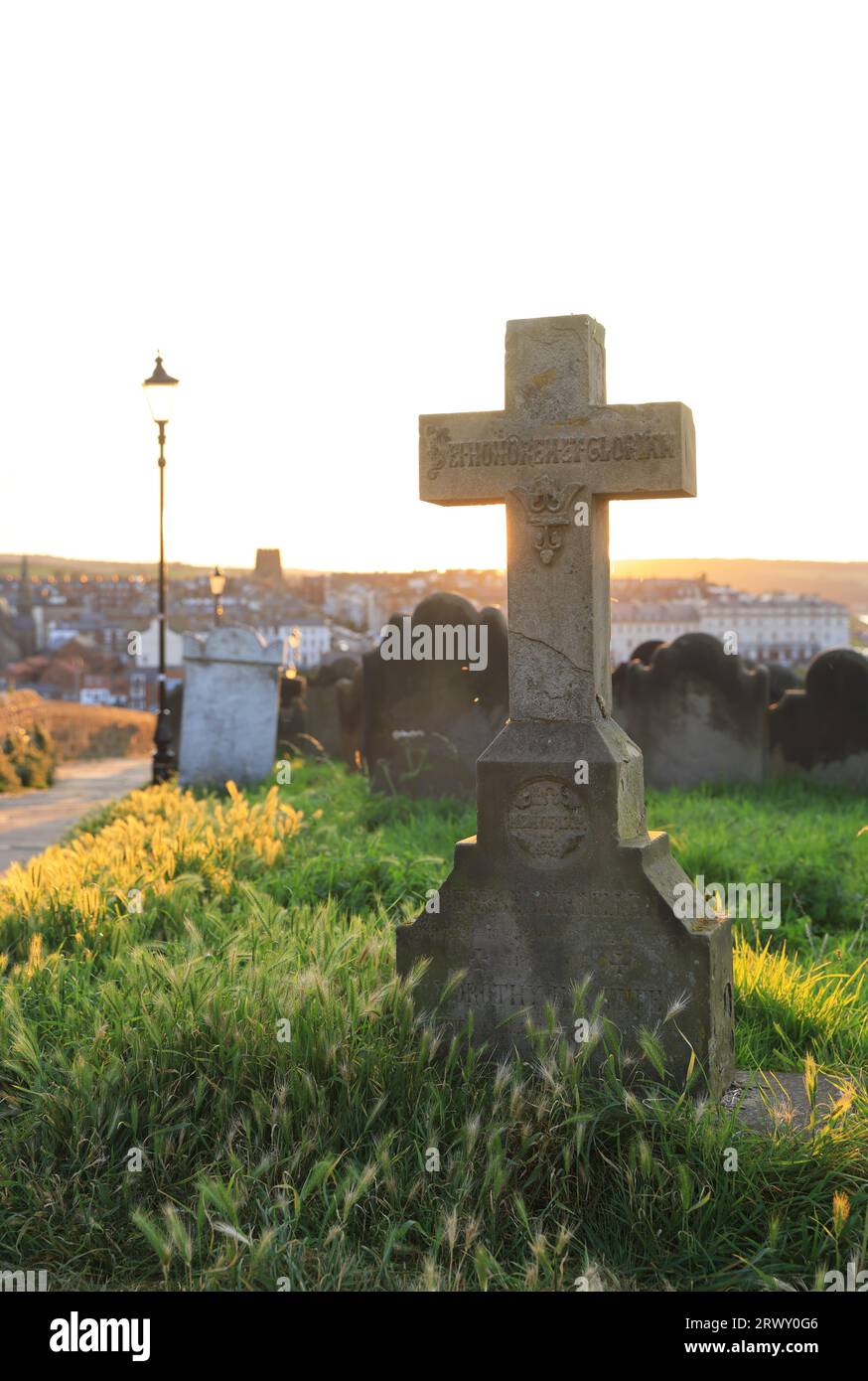 Sunset over the graveyard of historic St Mary's Church on windswept East Cliff by Whitby Abbey in North Yorkshire, UK Stock Photo