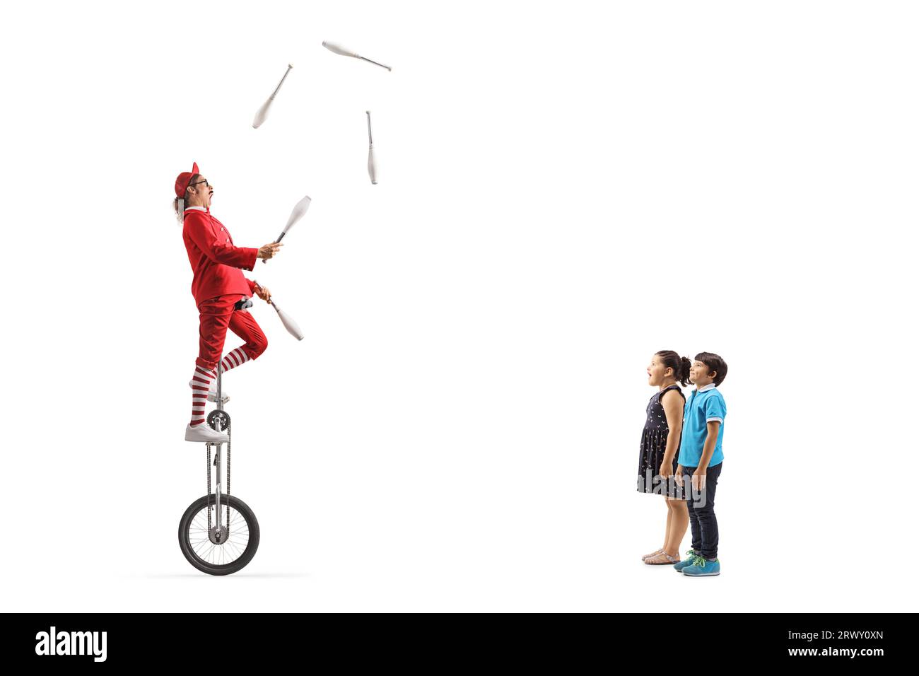 Children watching an acrobat riding a giraffe unicycle and juggling