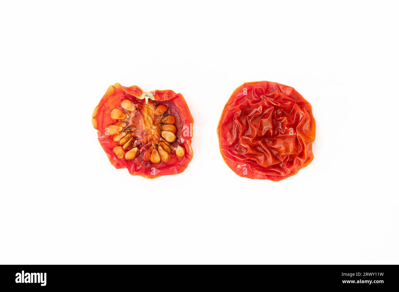 A dried cherry tomato sliced in half on white background Stock Photo