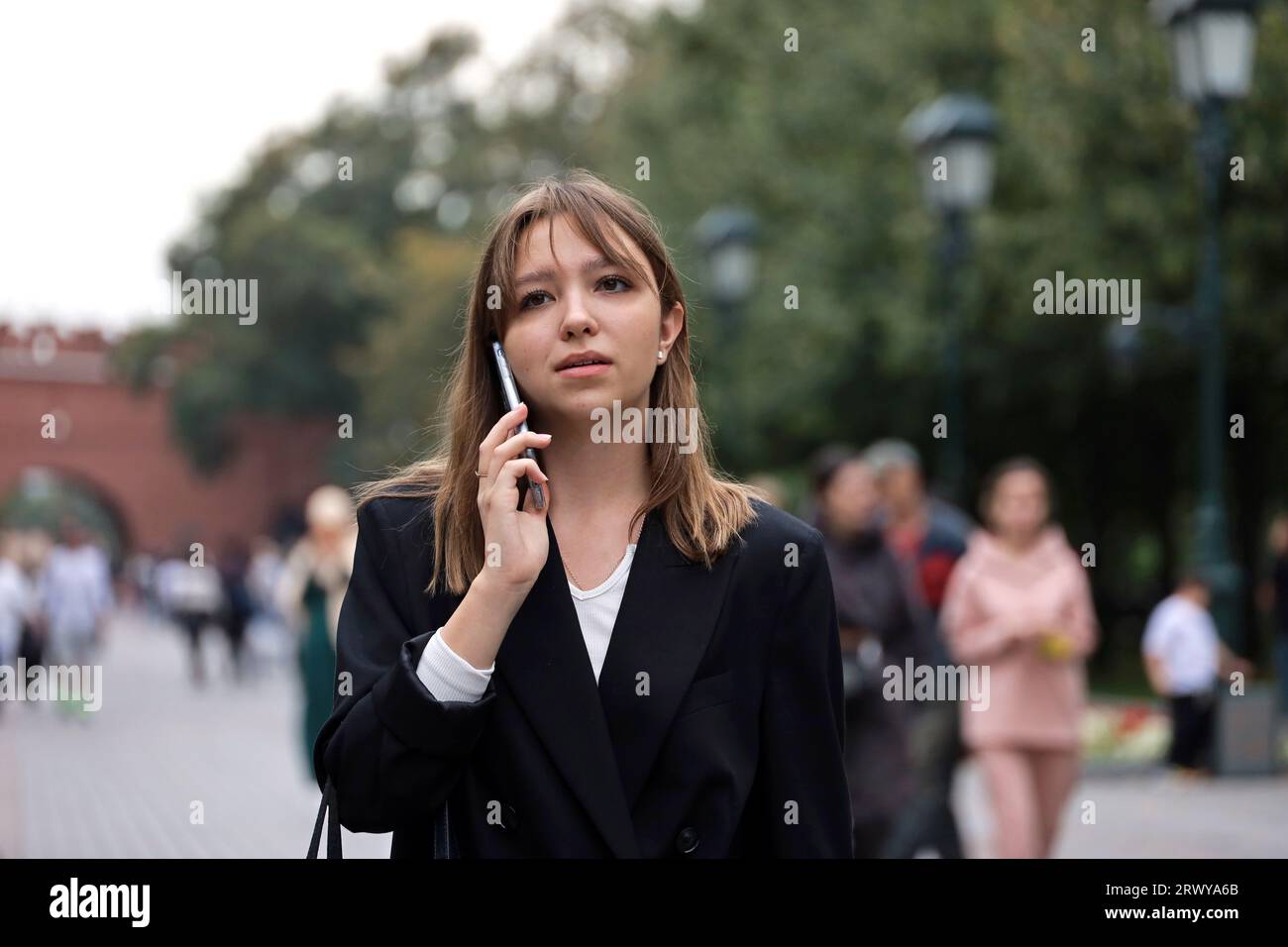 Girl talking on mobile phone while walking on city street Stock Photo
