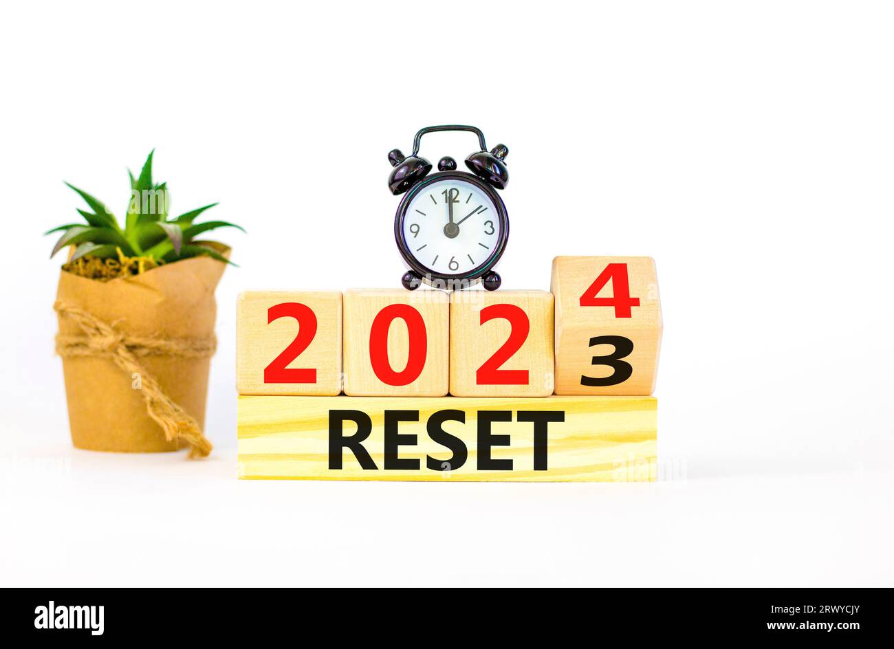 2024 reset new year symbol. Businessman turns a wooden cube and changes words Reset 2023 to Reset 2024. Beautiful white table white background, copy s Stock Photo