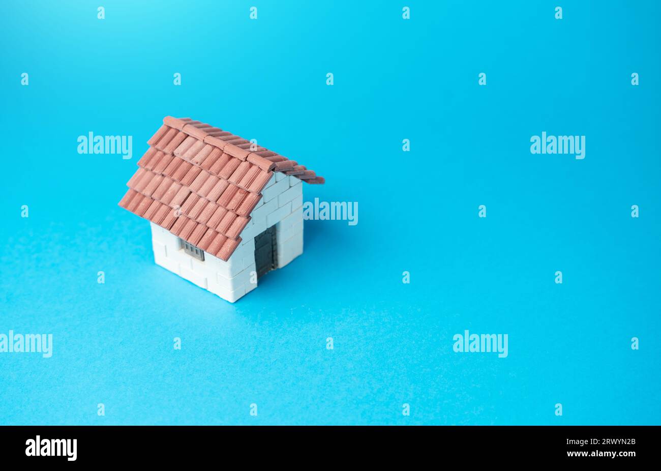 Miniature house on a blue background. Buying and selling housing. Design and architectural services. Property insurance. Real estate market review. Co Stock Photo