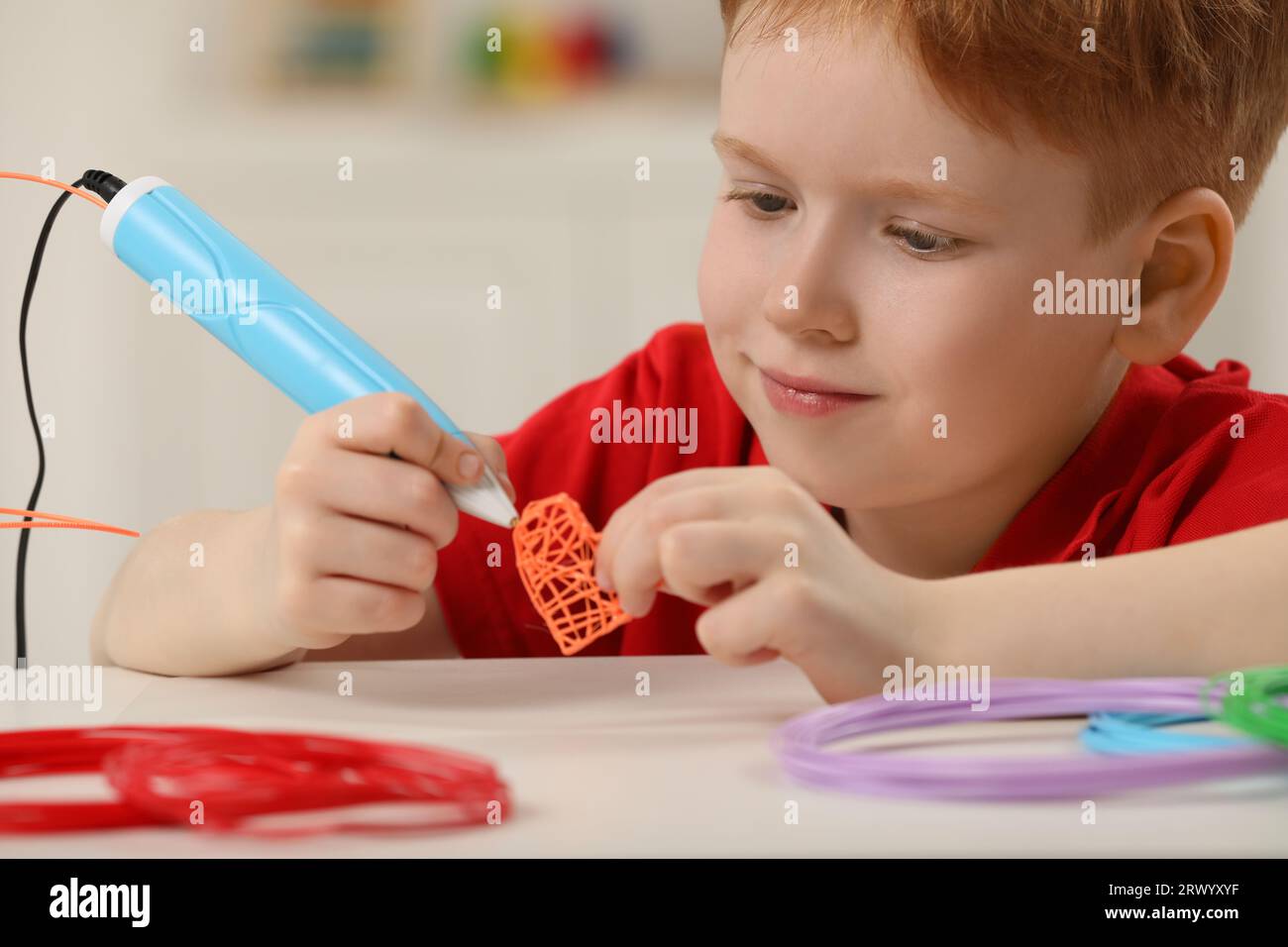 Boy drawing with stylish 3D pen at white table Stock Photo