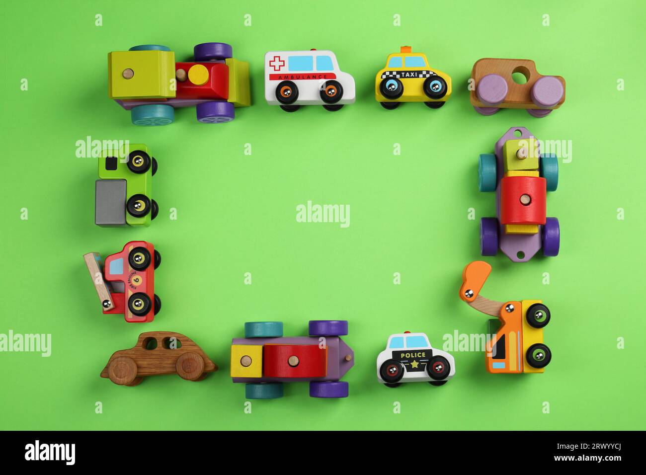 Frame of different toy vehicles for children on green background, flat lay. Space for text Stock Photo