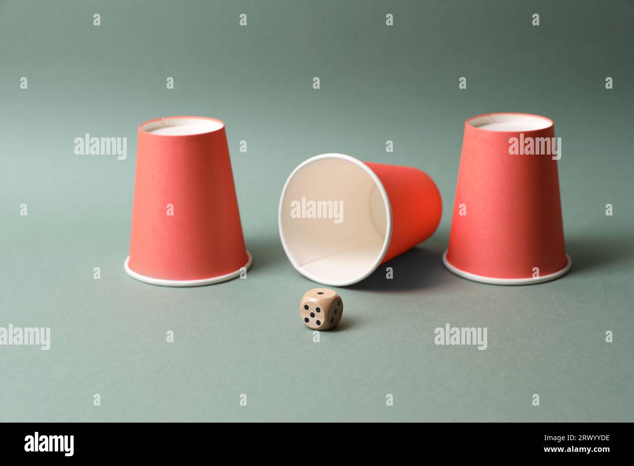 Three red cups and dice on pale olive background. Thimblerig game Stock ...