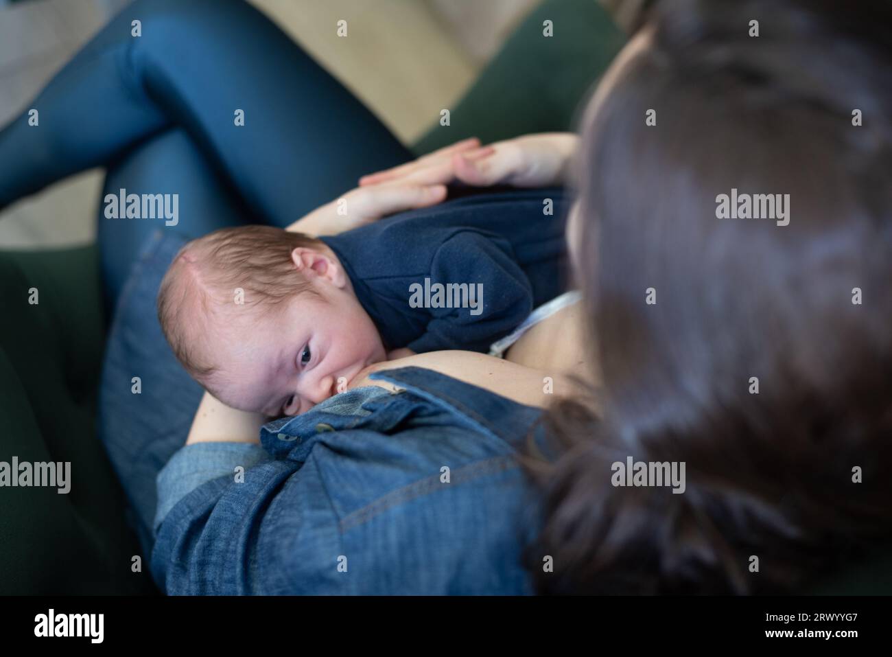 Brazilian mother breastfeeding her baby son while sitting on armchair