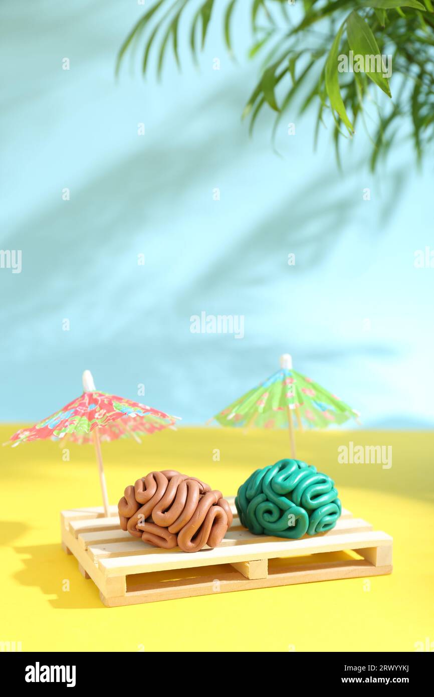 Brains made of plasticine on mini wooden sunbed under umbrellas against