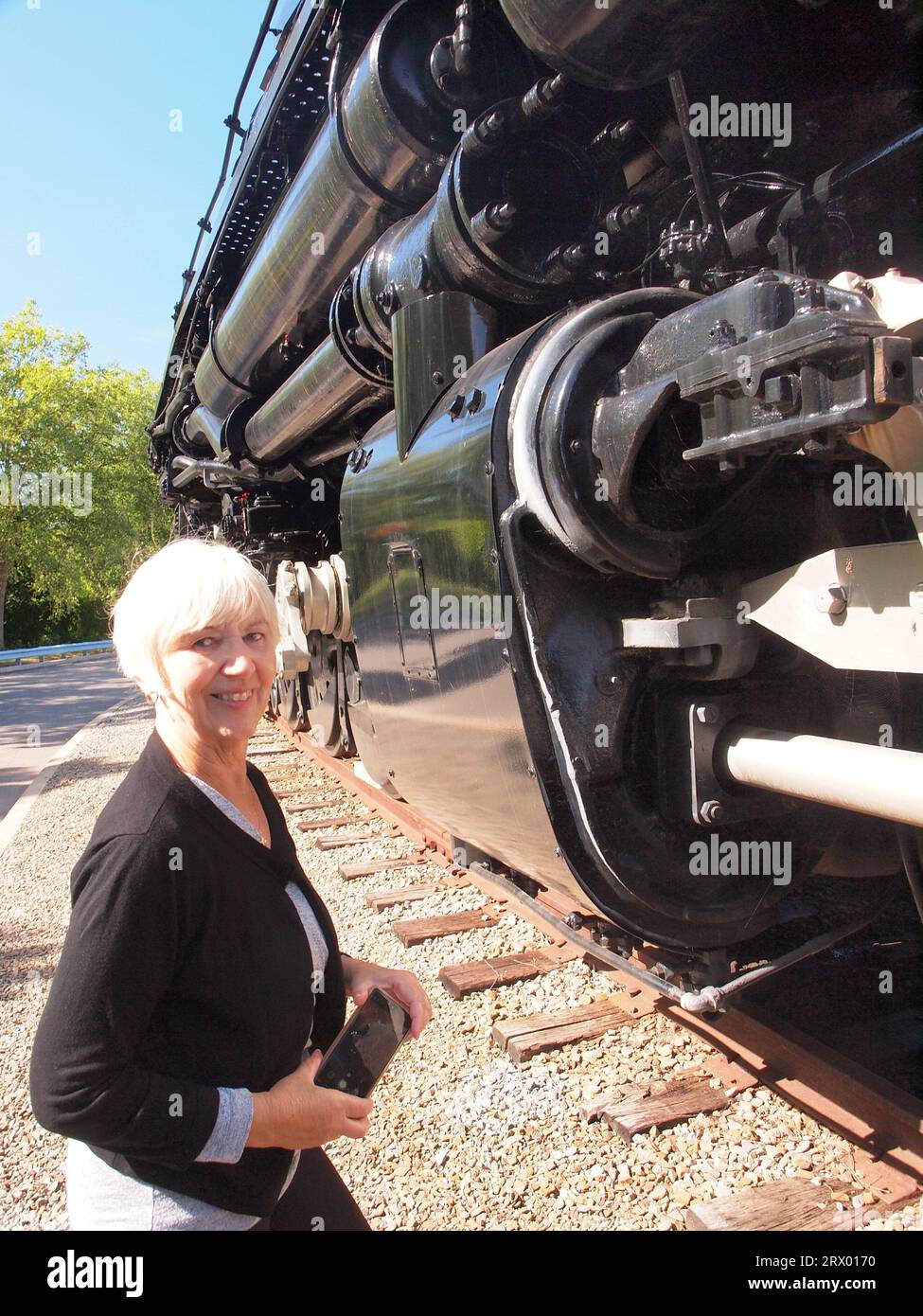 Attractive lady standing next to an enormous steam locomotive in Steam Town a National Park Service site in Pennsylvania. The Big Boy loco dwarfs all. Stock Photo