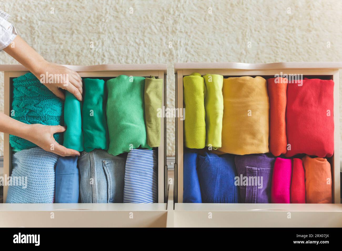 Women's hands take bright rainbow clothes from a wardrobe drawer. The ...