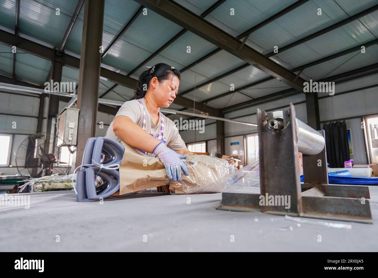 Luannan County, China - August 31, 2022: Workers are working nervously on a steel shovel assembly and packaging production line at a hardware tool man Stock Photo