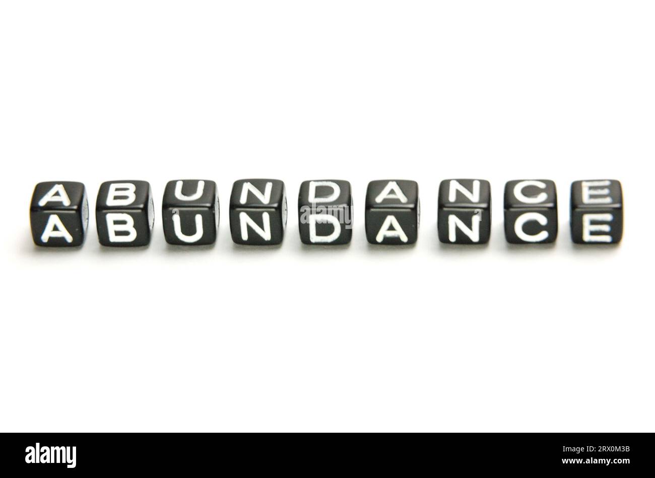 The word Abundance on the black dice. The situation in which there is more than enough of something Stock Photo