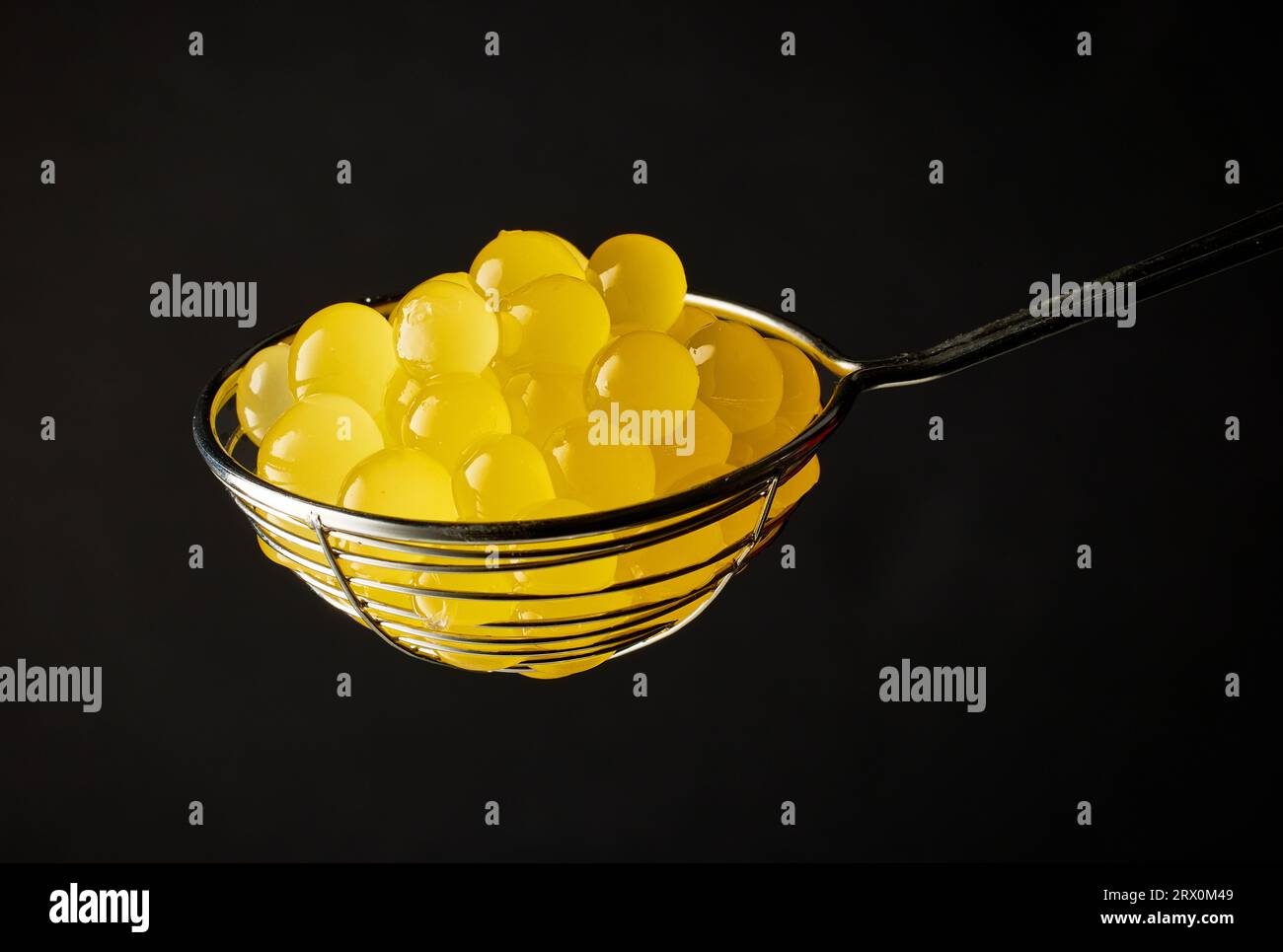 yellow jelly balls for making bubble tea in strainer on black