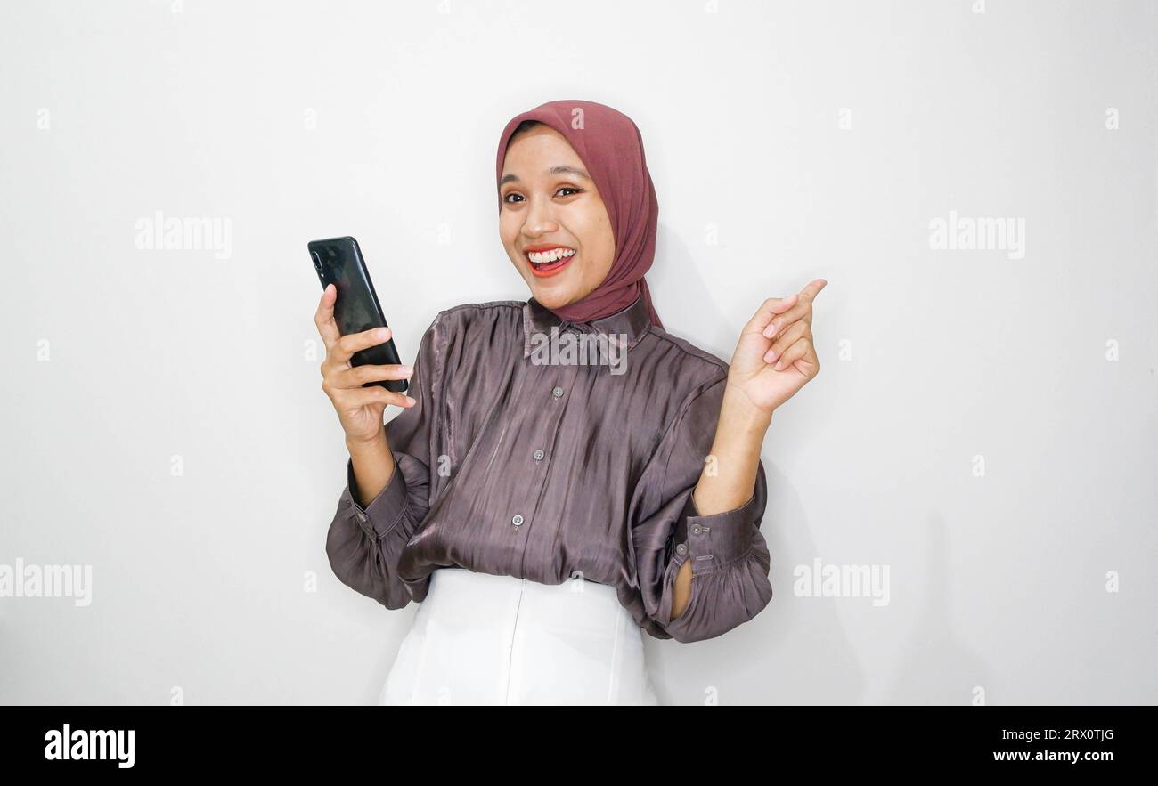 Portrait of happy young muslim woman talking on mobile phone against ...