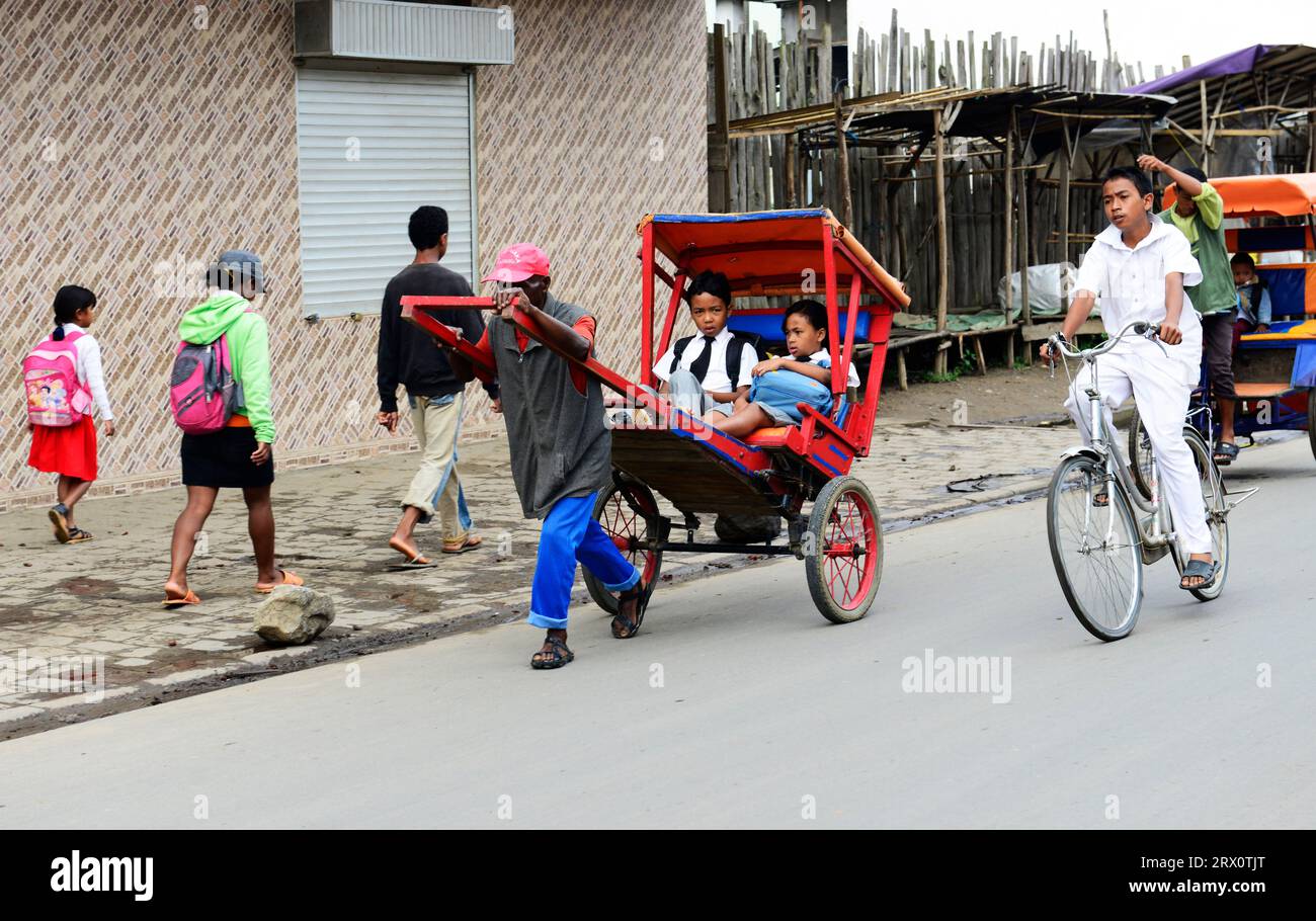 Malagasy primary school children going to school in a pousse pousse in ...