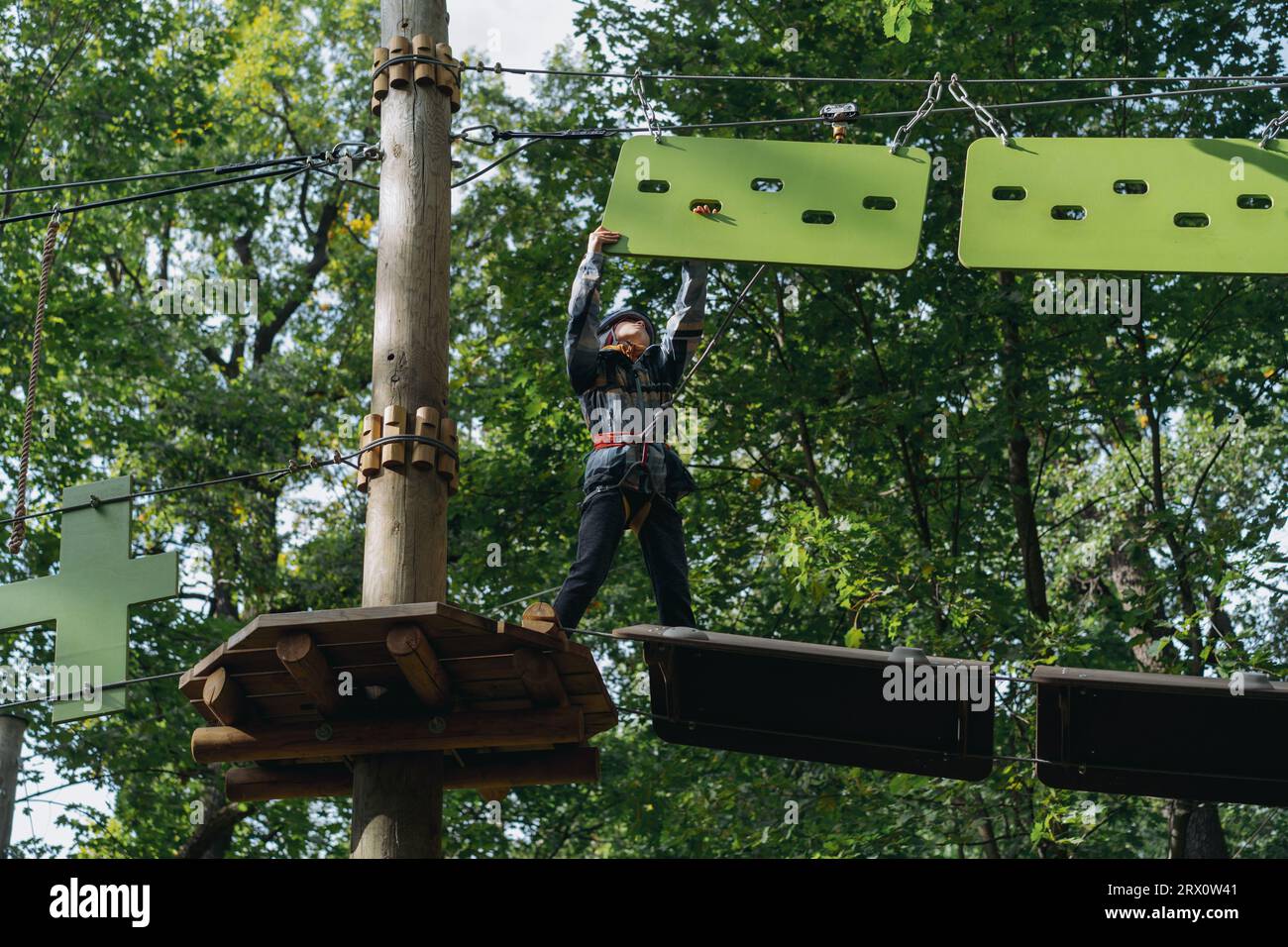 teenage boyin outdoor adventure park passing obstacle course. high rope ...