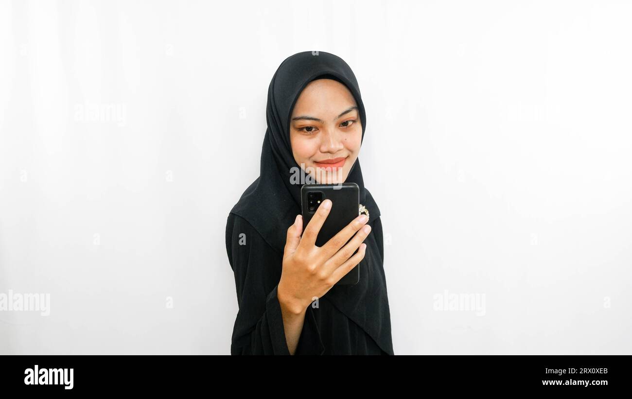 Cheerful young Asian woman taking selfie, look smartphone front camera isolated over white background Stock Photo