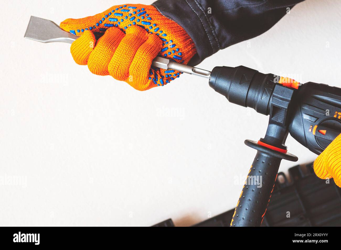 close-up. hands in protective gloves, hammer drill, installation of a chisel in a perforator. The concept of replacing the rotary drill. Stock Photo