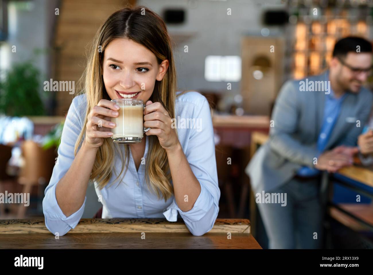 Portrait of happy young business woman drinking coffee in a break. In the background, her colleagues Stock Photo
