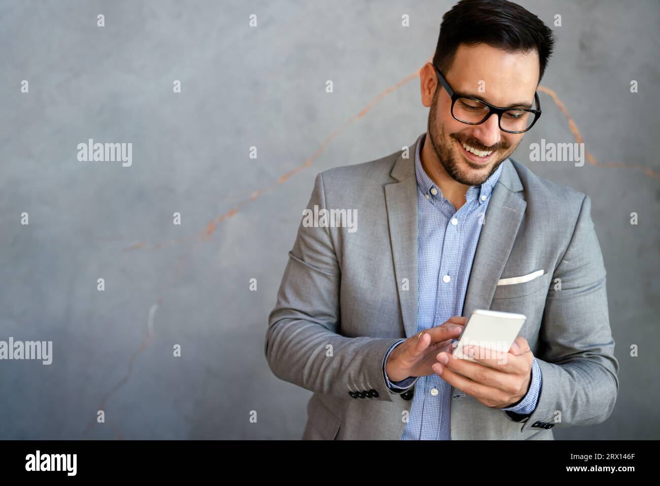 Handsome businessman checking emails on the phone in modern office in coffee break Stock Photo