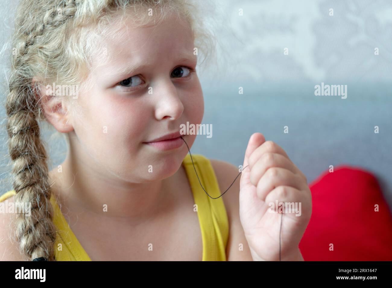 girl holds thread to pull out a milk tooth. Removal of tooth at the ...