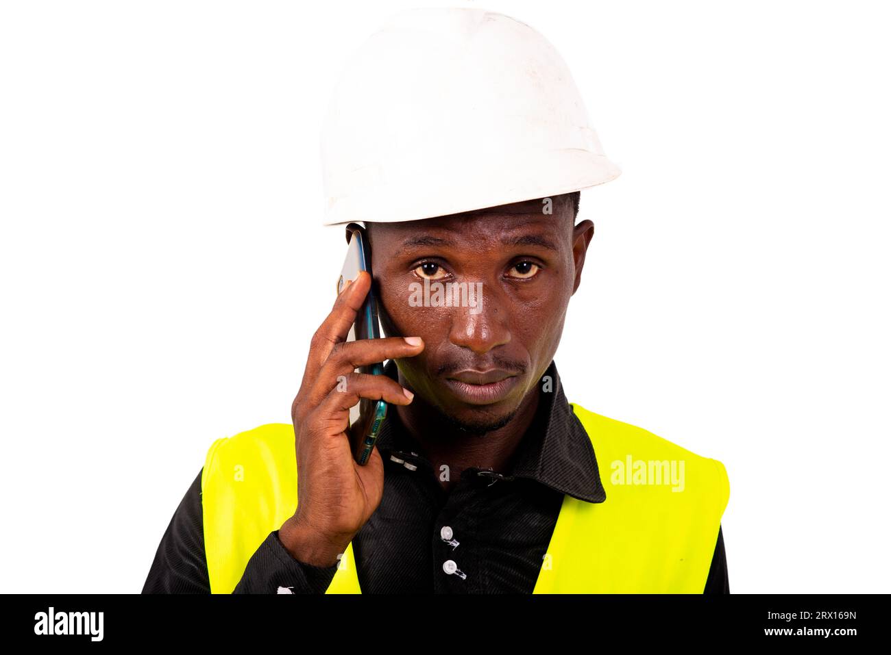 young man engineer wearing green vest and safety helmet while talking on mobile phone. Stock Photo