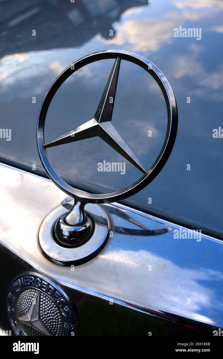 Iconic 1970s Mercedes badge on a car with blue sky reflected on bonnet, Cheshire, England, UK Stock Photo