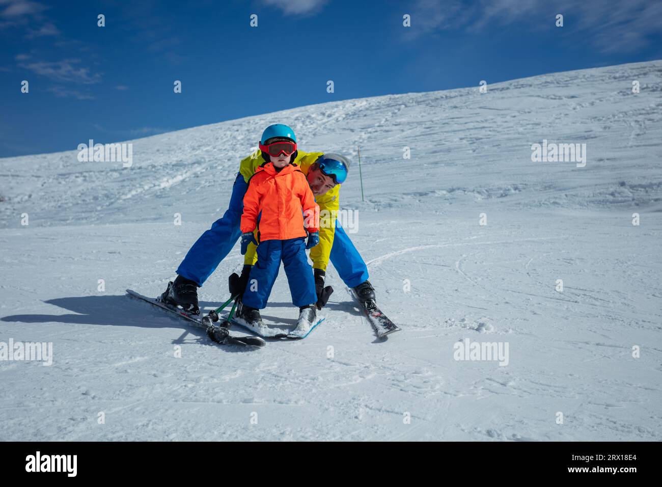 Dad teach boy glide behind hold ski bindings with hands Stock Photo