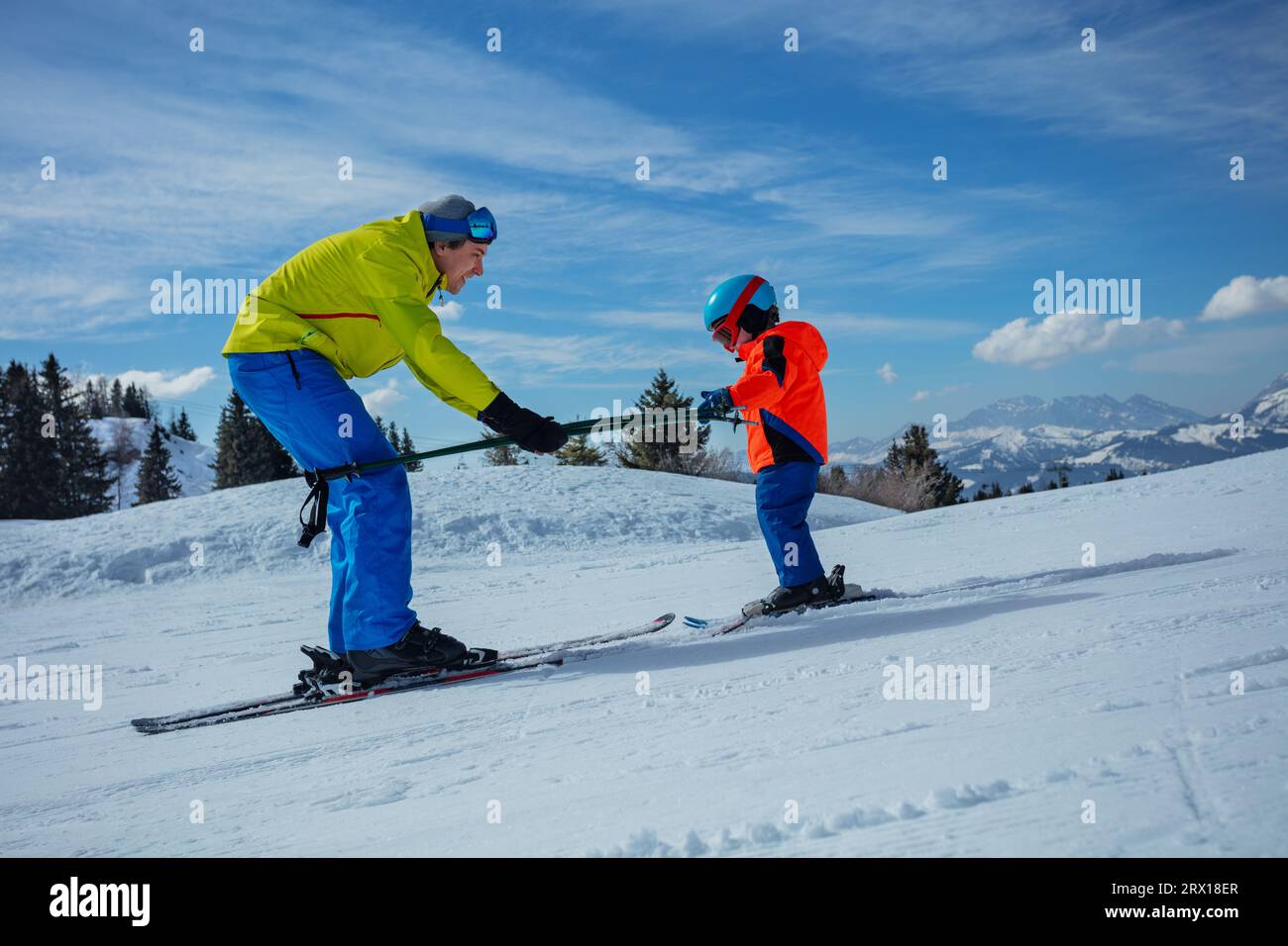 Instructor in skiing school glide backwards teach child to ski Stock Photo