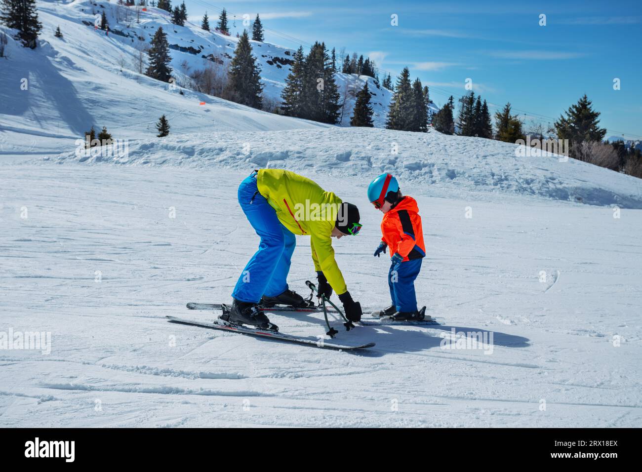 Man teach child ski holding skis with hands show snowplow move Stock Photo