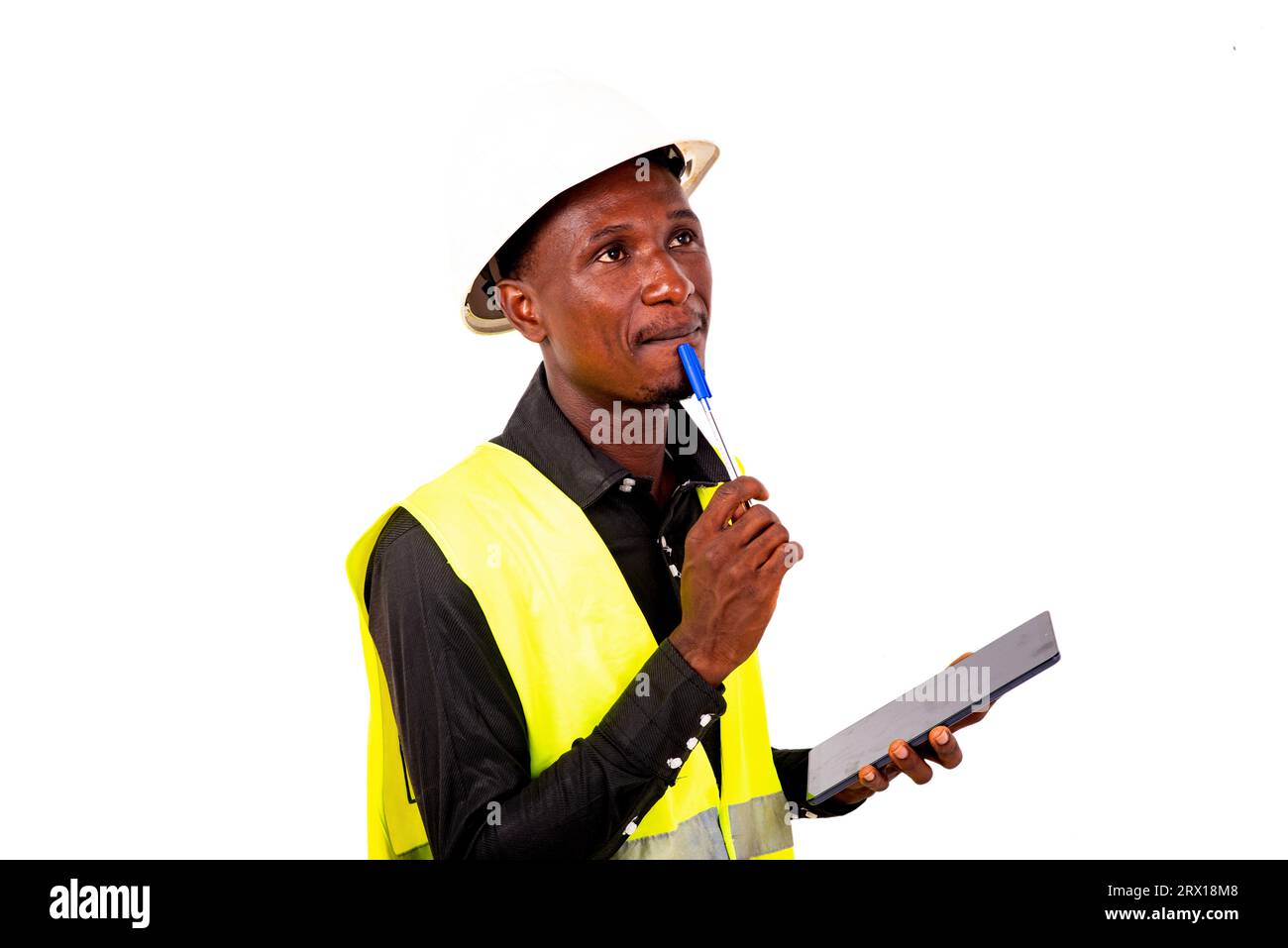 a construction engineer with safety helmet standing on white background thinking while holding a tablet. Stock Photo