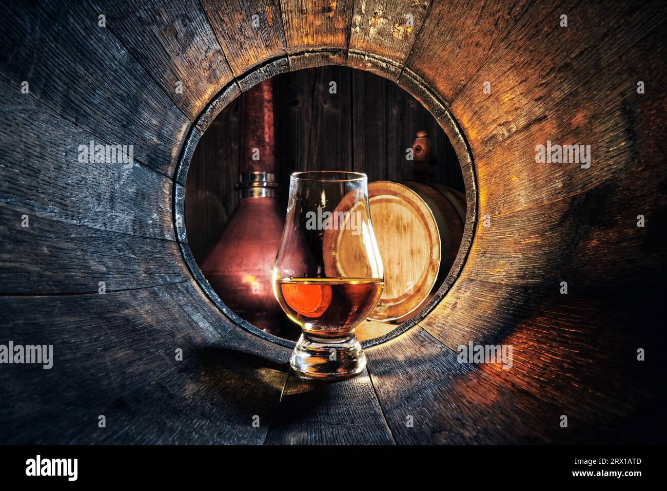 A glass of whiskey in old oak barrel. Copper alambic on background