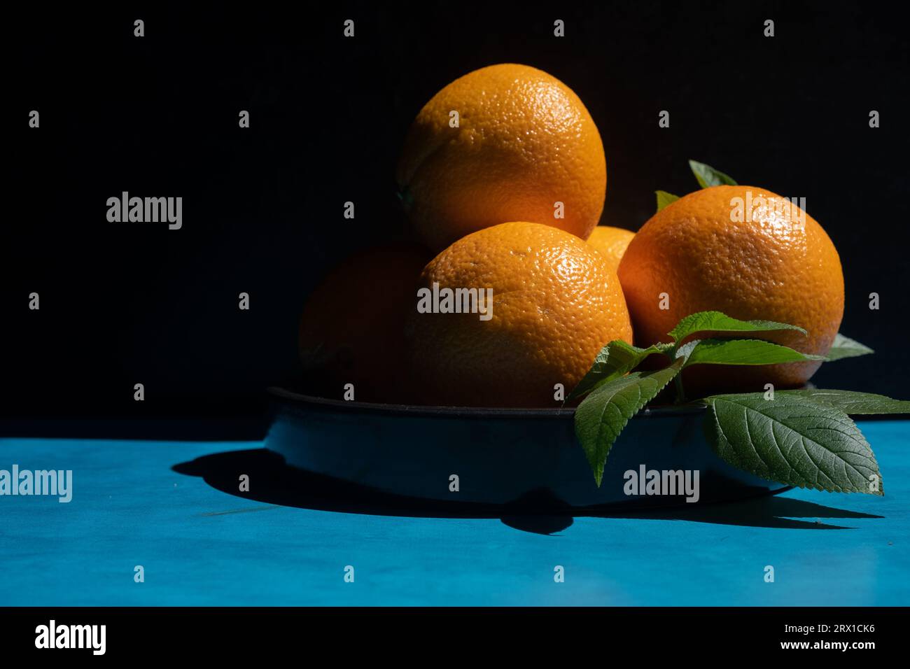 Bowl of oranges on a blue table. Stock Photo